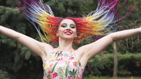 A Girl with a Happy Smile in a Dress with African Braids and Makeup Whirls and Throws Her Hair Up in