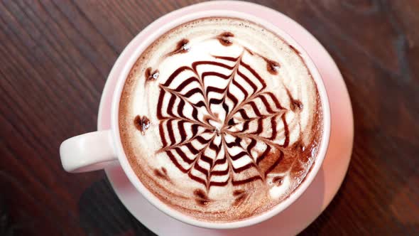 Top View of Pink Cup of Coffee with Latte Art From Chocolate Syrup in Cafe