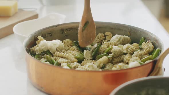 Crop woman mixing pasta in sauce pan