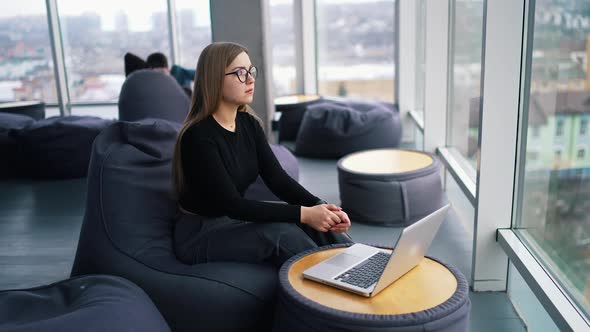 young woman wearing eyeglasses working on laptop computer