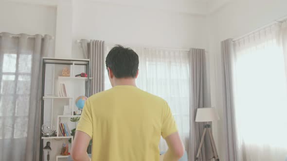 Back View Of Asian Man Running On A Treadmill At Home