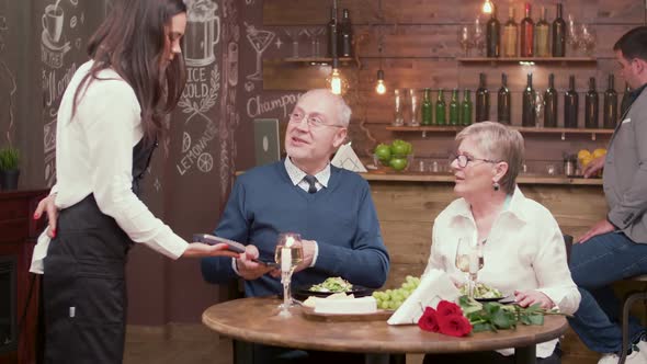 Old People in a Restaurant Using New Technology To Pay the Bill