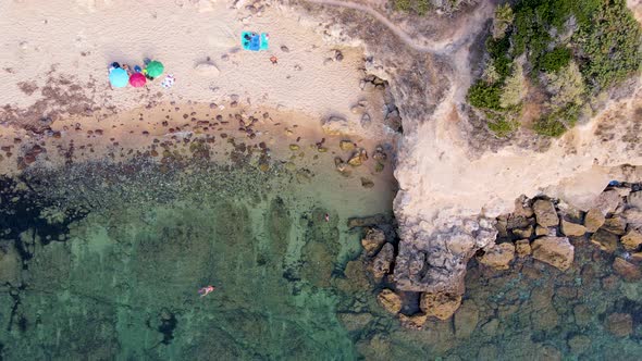 Ascendant aerial drone view of coastline with people sunbathing and relaxing