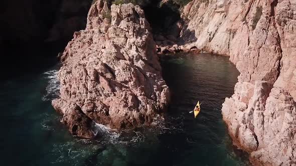 Flying behind a young man arribing with his kayak to a mediterranean cove