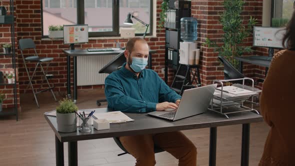 Employee Checking Data Rate Charts on Papers and Laptop