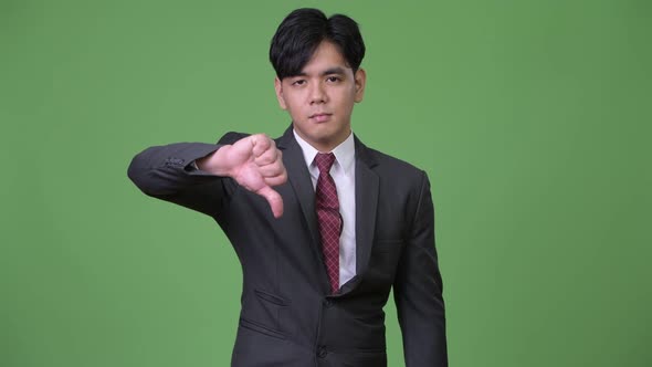 Young Handsome Asian Businessman Giving Thumbs Down