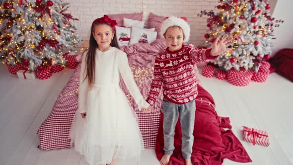 Portrait of Attractive Cute Kids Wearing Christmas Wear Falling Together on Bed in Apartment