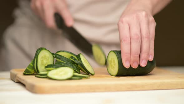woman slicing cucumber on kitchen board