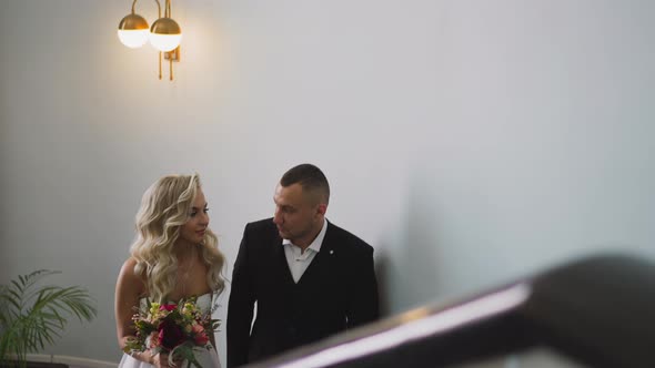 Positive Newlywed Couple Goes Up Stairs in Hotel Building