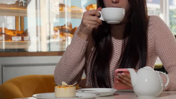 Unrecognizable Woman Using Smart Phone While Drinking Hot Tea at the Coffee Shop