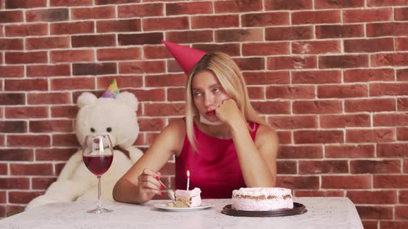 Upset Young Woman Celebrates Birthday in Quarantine Slowly Breaking Off a Piece of Cake with a Spoon