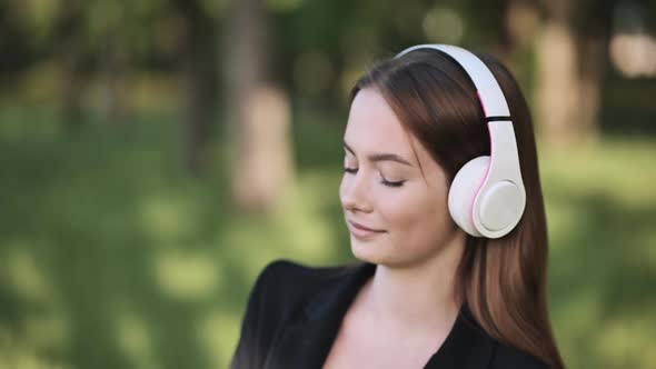 A Girl Wearing Headphones Listening to Music in a City Park