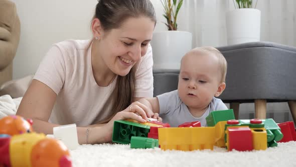 Little Baby Boy with Mother Playing Toys on Carpet in Living Room