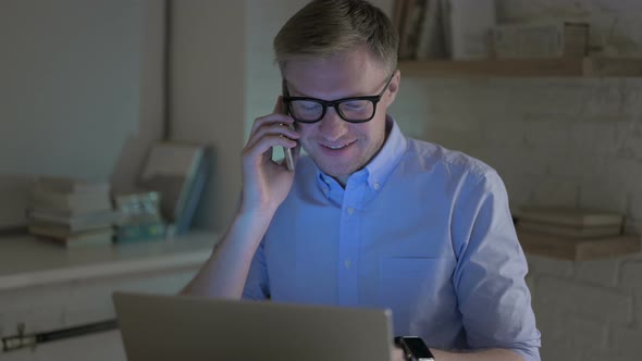 Businessman Speaking on Phone While Working Late Night