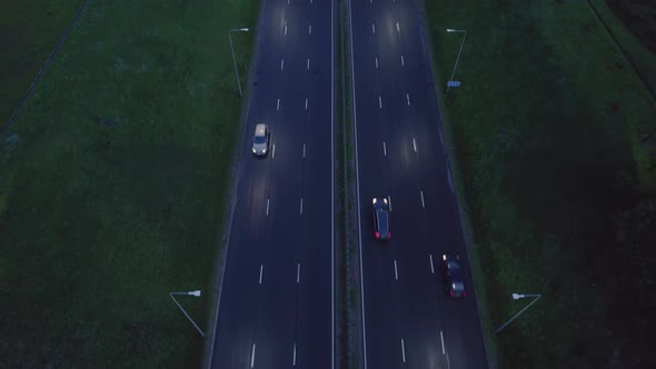 Aerial drone view of a multi-level highway crossroad with moving cars at sunset. Cars are moving alo