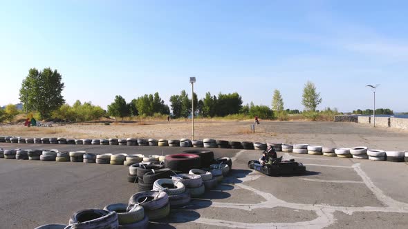 Young Go Cart Race on Circuit Outdoors. There Are Safety Barriers Made of Old Wheels . Ten Years Old