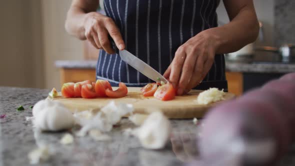 Mid section of caucasian senior woman wearing aprons chopping vegetables in the kitchen at home