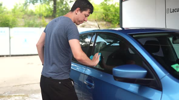 Man Cleaning Car and Drying Vehicle with Microfiber Cloth