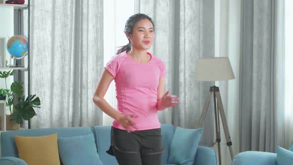 Asian Girl In Sportswear Is Energetically Jogging In Place In Her Living Room