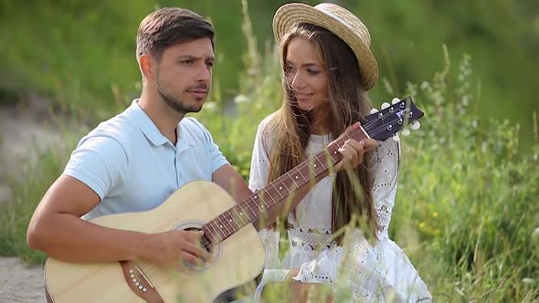Romantic Man Playing On Guitar For Woman In Nature