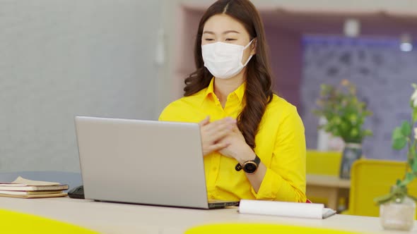 asian business woman wears yellow shirt and face mask meeting online video conference call