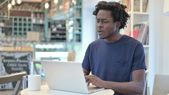 Successful African Man Celebrating on Laptop in Cafe