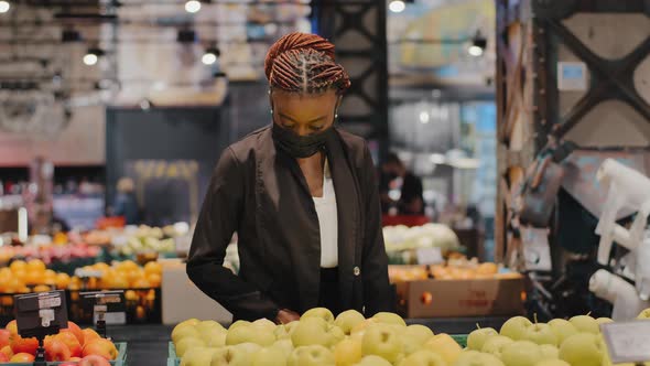 Young African American Girl Woman Shopper Consumer in Medical Mask in Store Chooses Products Apples