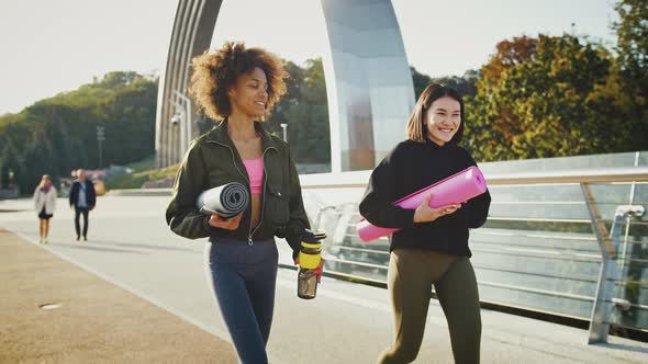 Smiling Diverse Female Friends Going for Workout Holding Yoga Mats and Talking