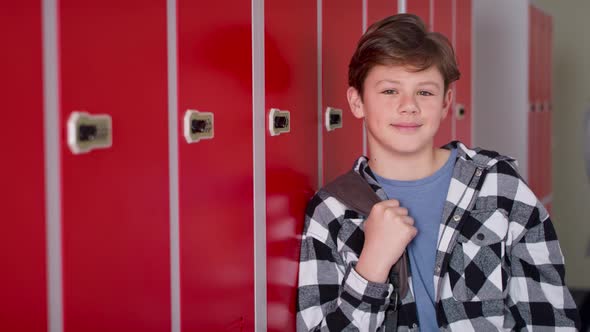 Video portrait of smiling teenager standing in corridor near lockers.