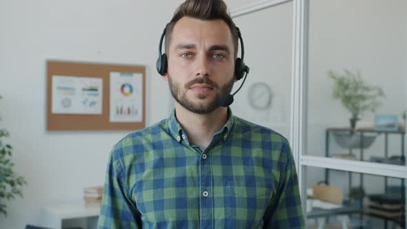 Slow Motion Portrait of Handsome Guy Wearing Headphones with Microphone Standing in Office