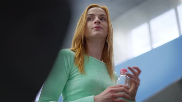 Portrait of Charming Fit Slim Sportswoman with Water Bottle Running on Treadmill in Gym