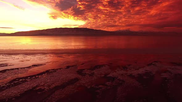 Flying over frozen lake during colorful sunset