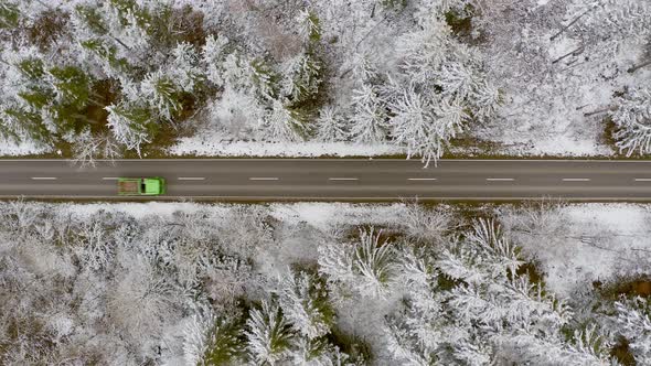 Following a green lorry by drone from above, driving through a winter landscape as top shot in 4K