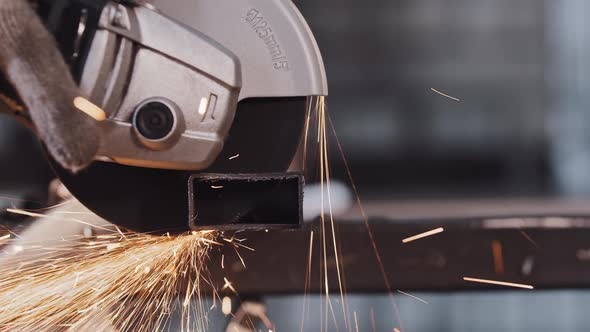 Manufacturing Plant  Worker Cutting the Part of Metal Detail with Angle Saw  Bright Sparkles