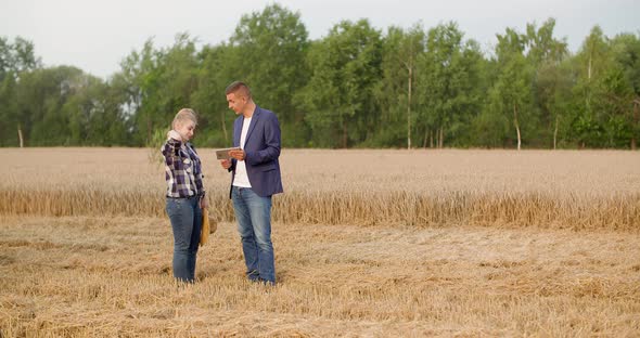 Agriculture - Female and Male Farmers Talking at Wheat Field During Harvesting