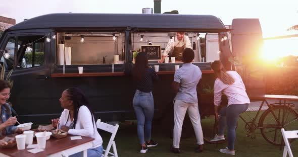 Young man chef working inside food truck preparing dinner food - Multiracial people ordering meal