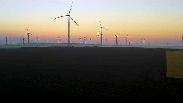 Eolian turbine farm at sunrise. Wind turbine silhouette. Wind field turbines