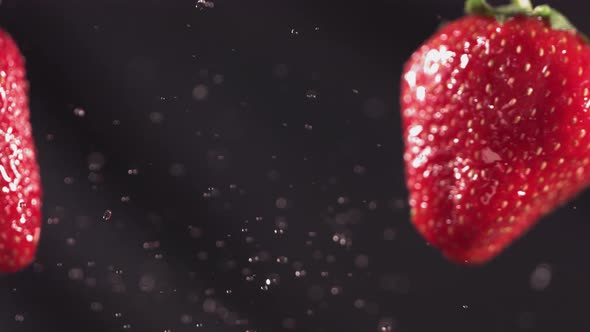 Two Big Strawberries are Flying and Colliding on a Black Background