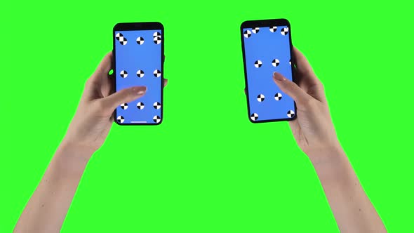 Woman Holds Two Smartphones on Green Screen Background with Alpha Compositing on Displays