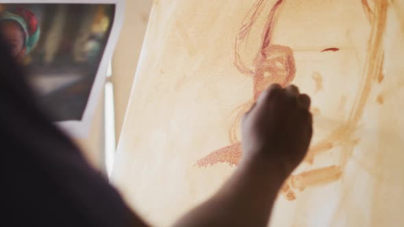 African american male painter painting from photograph on canvas in artist studio