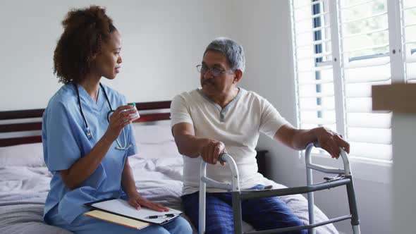 Senior mixed race man with female doctor talking and holding pills