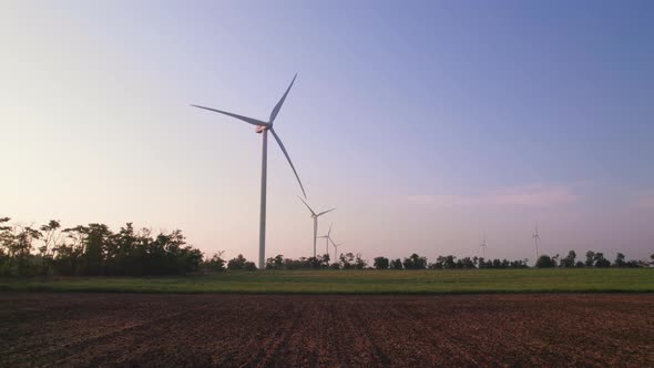 Windmills in a plowed field. Wind farm with turbine cables for wind energy.