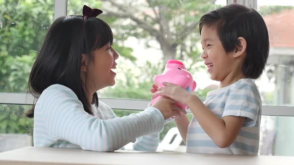 Cute Asian Child Putting A Coin In To A Piggy Bank Slow Motion