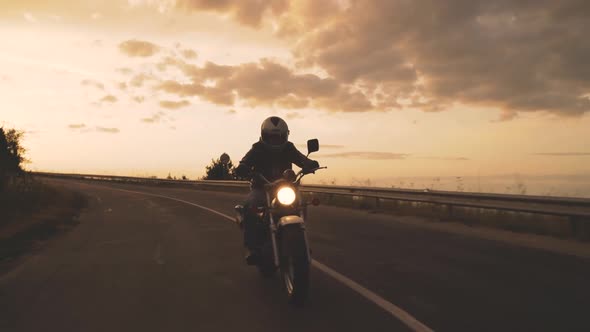 Motorcyclist Enjoys a Ride on His Motorbike at Sun Dawn on the Road to Freedom