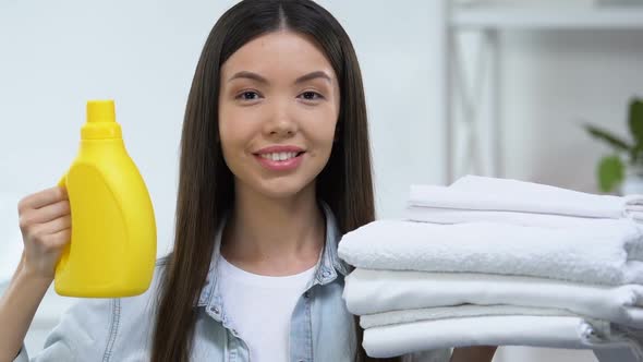 Satisfied Woman Showing Washing Gel and Fresh Linen Into Camera, Whitening