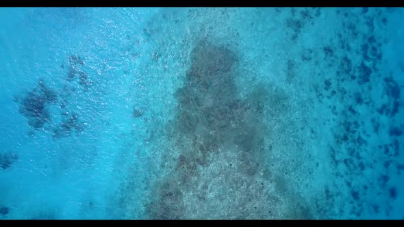 Aerial flying over landscape of tranquil coastline beach break by blue green sea with white sand bac