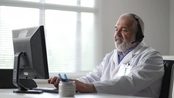 Male Doctor Sitting At The Table And Using Laptop