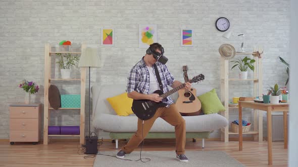 Young Man Musician in Virtual Reality Glasses Emotionally Playing the Electric Guitar