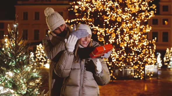 Man Giving Christmas Gift to Woman on City Street