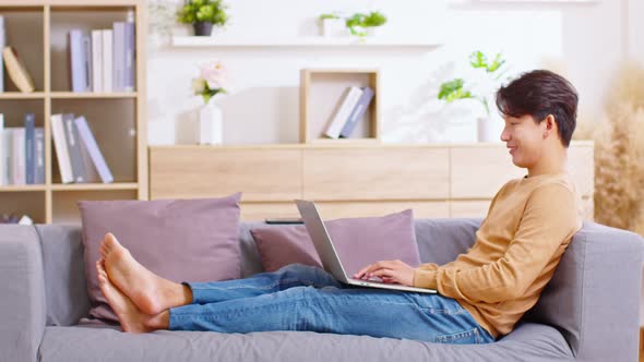 Entrepreneur handsome business asian man wear shirt lying on couch working online with computer lapt